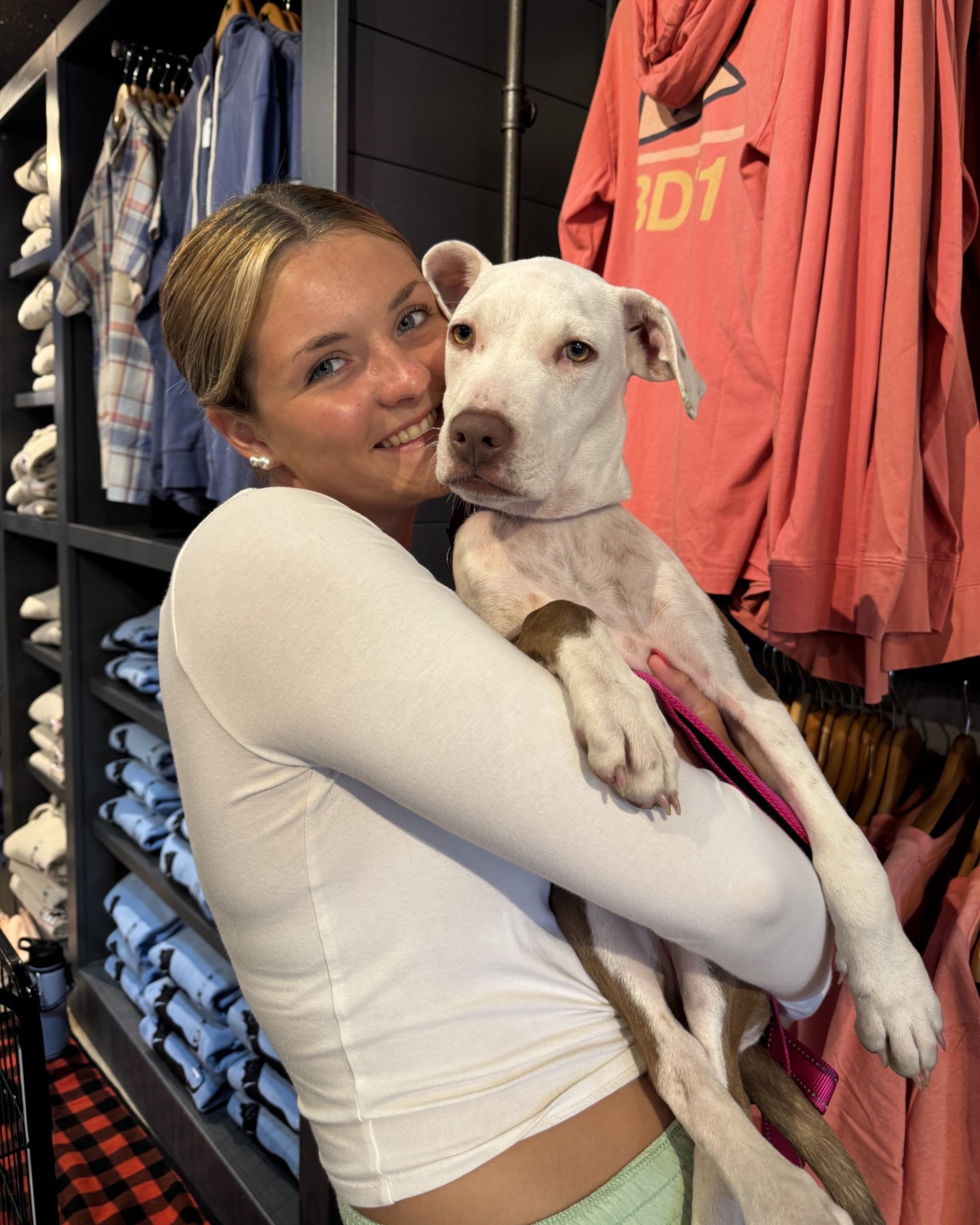 Woman holding a white dog in a clothing store